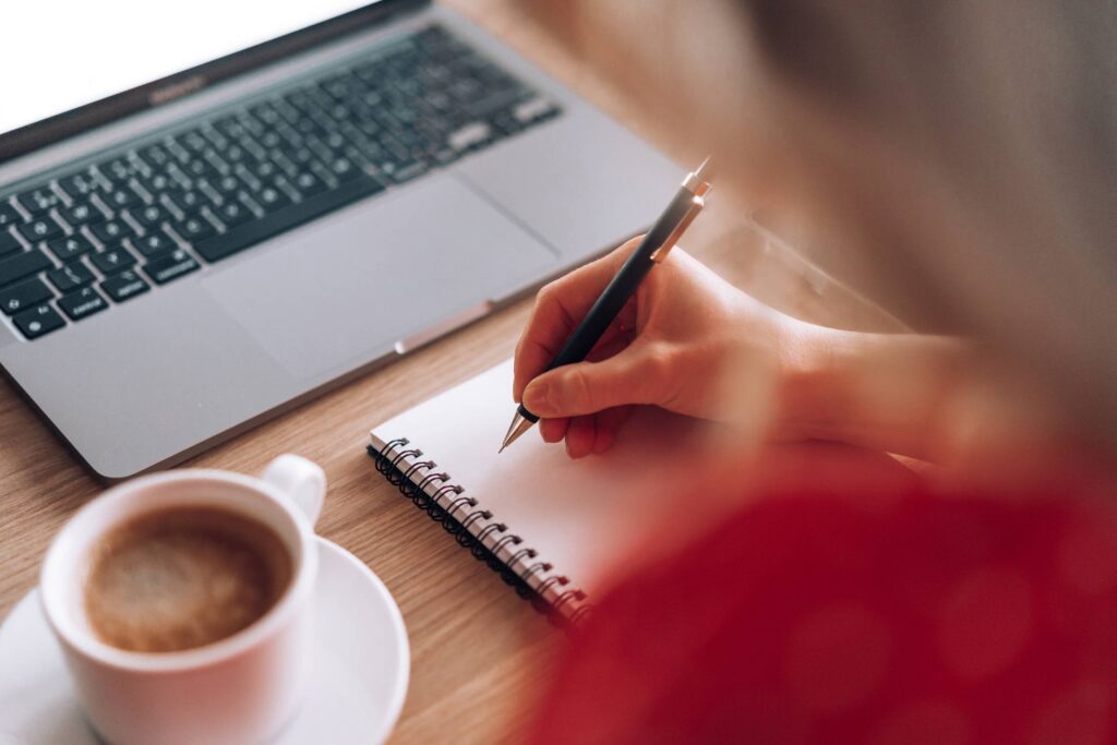 Woman Working on Laptop and Writing in Her Diary Free Photo