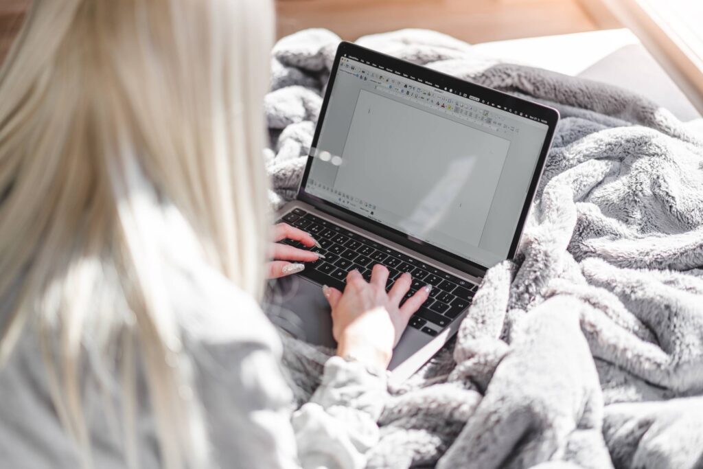 Woman Working with Spreadsheet on Laptop in Bed Free Photo