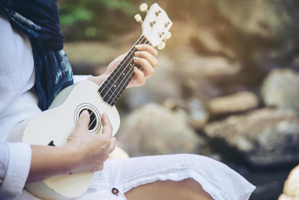 Women play ukulele new to the waterfall – people and music instrument life style in nature concept Stock Free