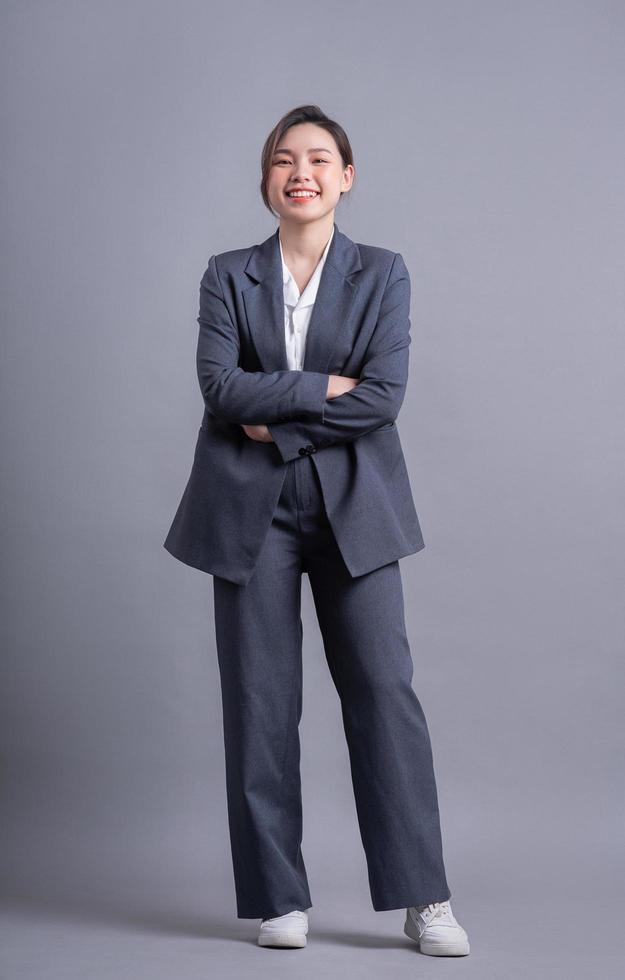 Young Asian business woman standing on gray background Stock Free