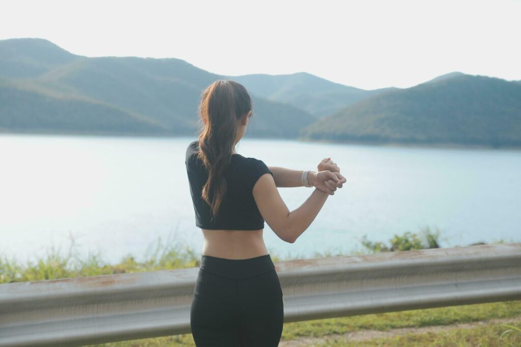 Young beautiful Asian woman in sports outfits doing stretching before workout outdoor in the park in the morning to get a healthy lifestyle. Healthy young woman warming up outdoors. Stock Free