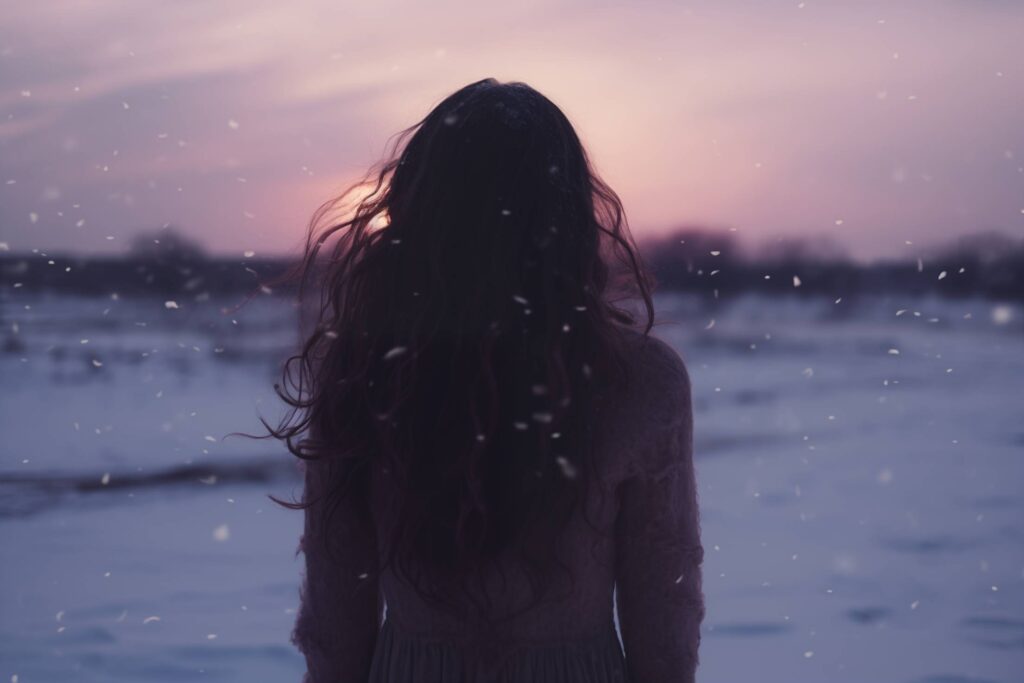 Young Brunette Woman in Sweater Standing with Her Back Turned in a Snowy Landscape Free Photo