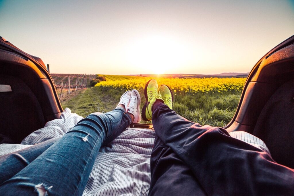 Young Couple Enjoying Romantic Sunset from Car Trunk Free Photo