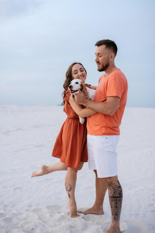 young couple in orange clothes with dog Stock Free