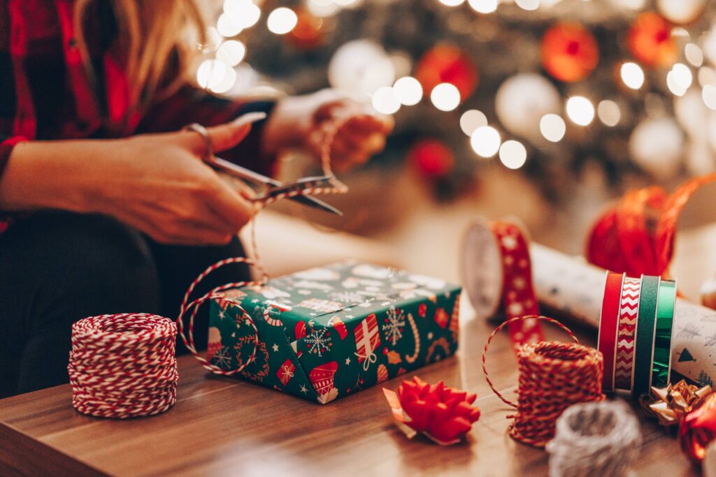 Young Mom Cutting a Ribbon for a Christmas Present Wrapping Free Photo