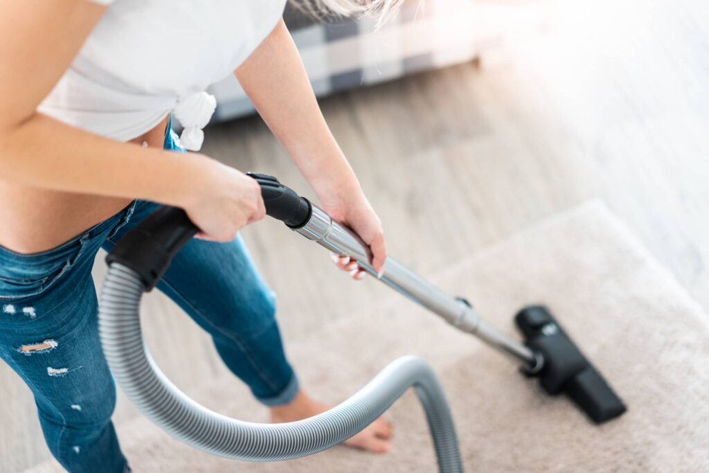 Young Woman Cleaning Carpet with Vacuum Cleaner Free Photo