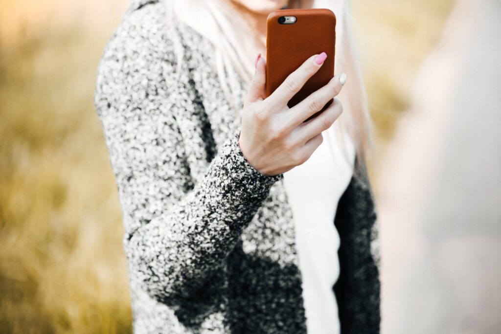 Young Woman Holding Her iPhone in Leather Case Free Photo