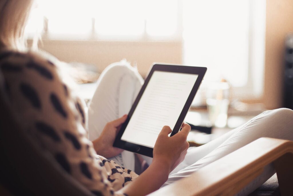 Young Woman Reading a Book on Her iPad Free Photo