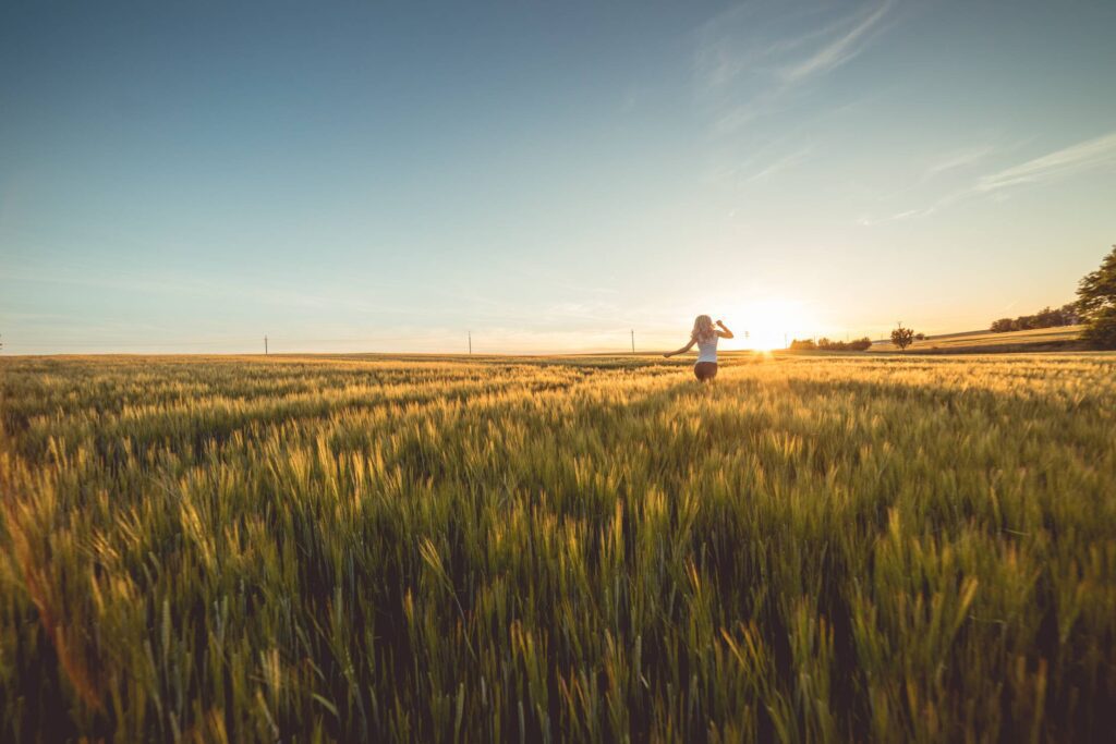 Young Woman Running Through Wheat Field on Sunset Free Photo