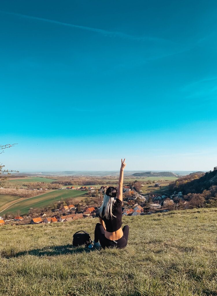 Young Woman Sitting on a Hill Showing Peace Sign Free Photo