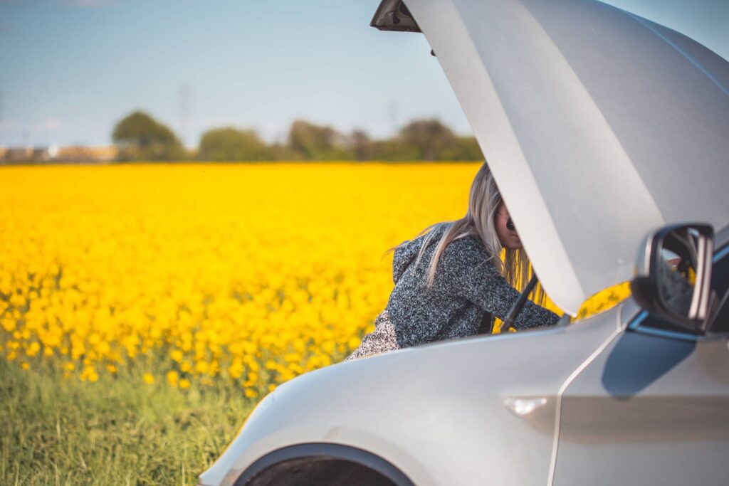 Young Woman Trying to Check and Repair Her Broken Car Free Photo