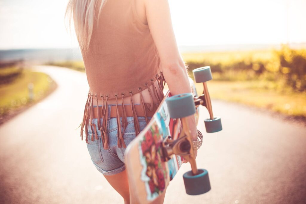 Young Woman Walking on The Road and Holding Longboard Free Photo