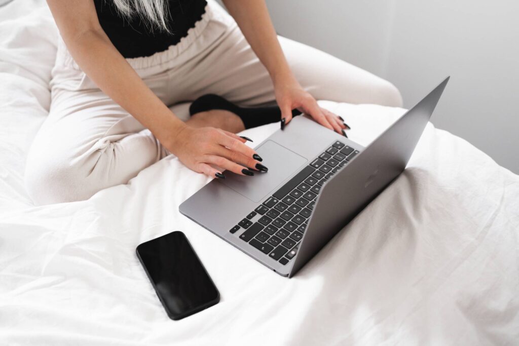 Young Woman Working on a Laptop in Bed Free Photo