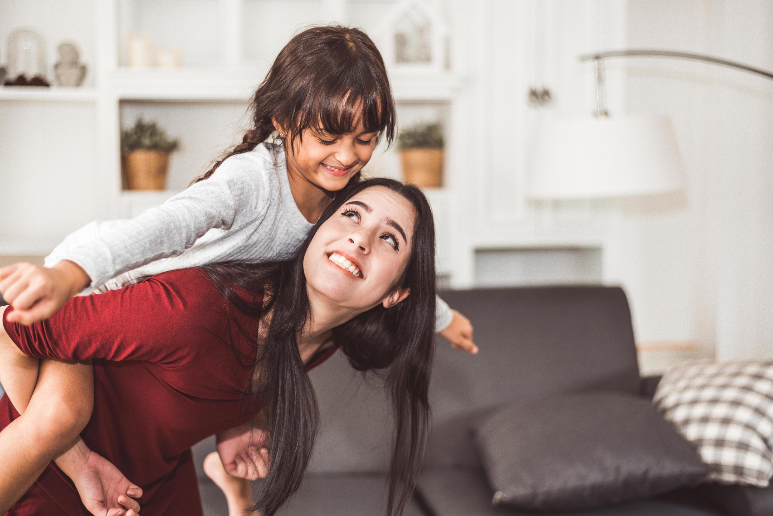 Mother giving daughter a piggyback ride Stock Free