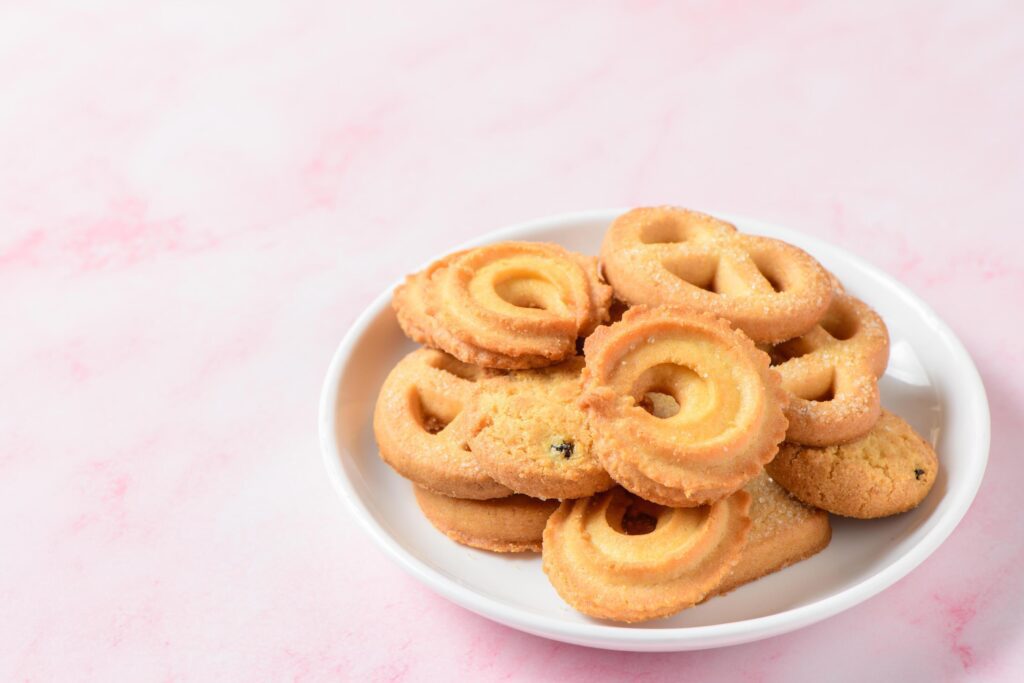 Set of danish butter cookies macro cutout. Five whole pretzel, round and rectangular shortbread biscuits with sugar on pink background. Stock Free