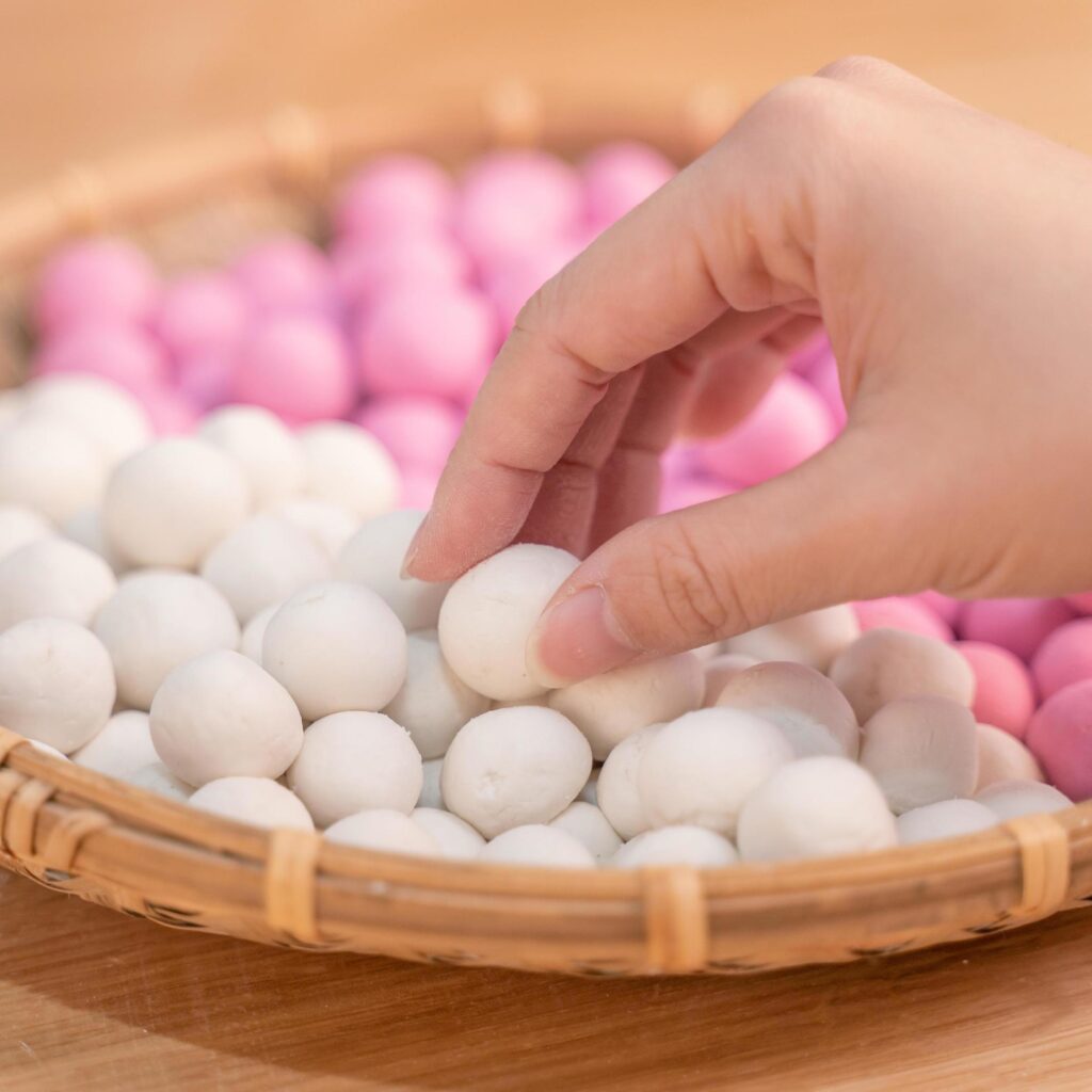 An Asia woman is making Tang yuan, yuan xiao, Chinese traditional food rice dumplings in red and white for lunar new year, winter festival, close up. Stock Free