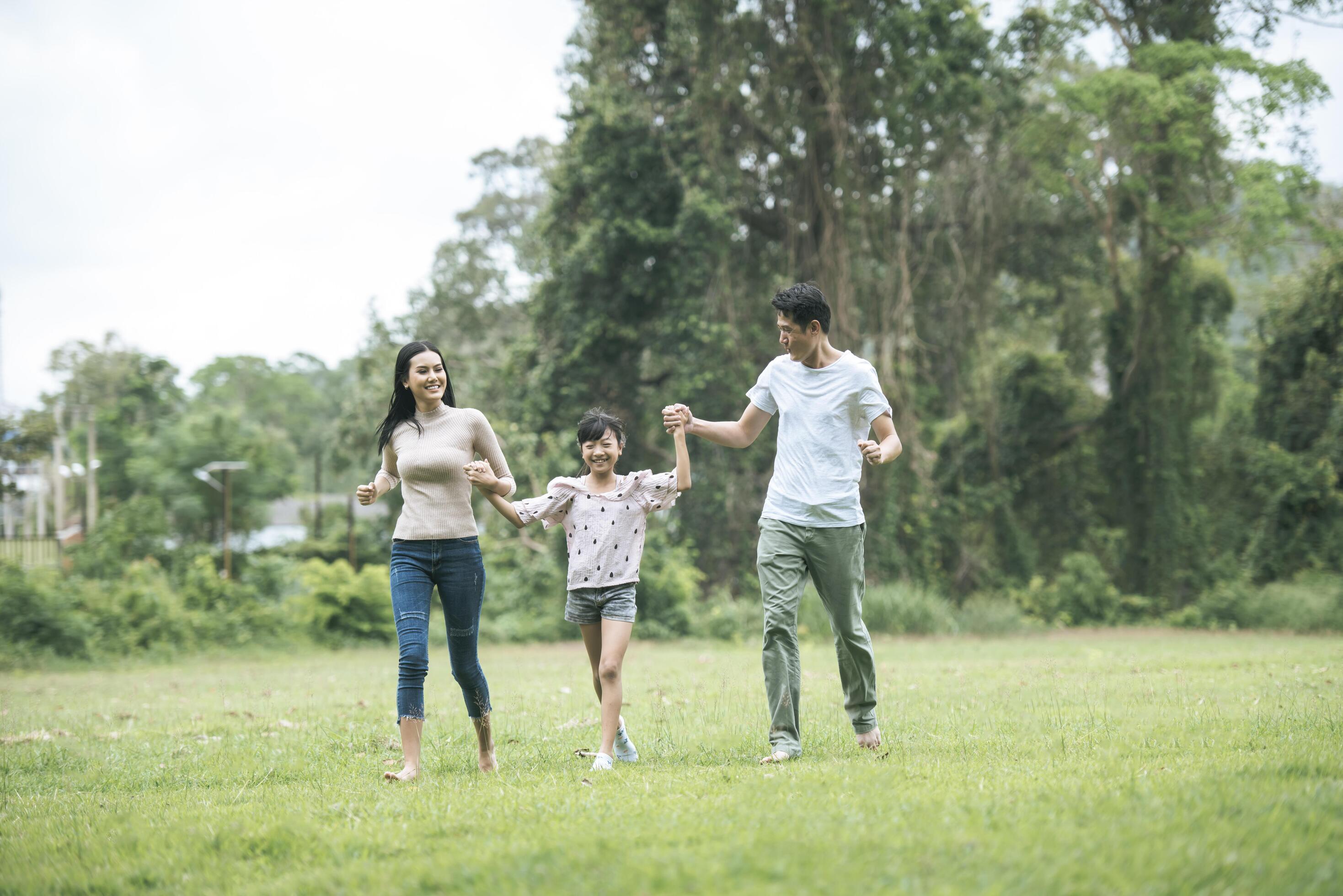 Happy parents and their daughter walking in the park, Happy family concept. Stock Free