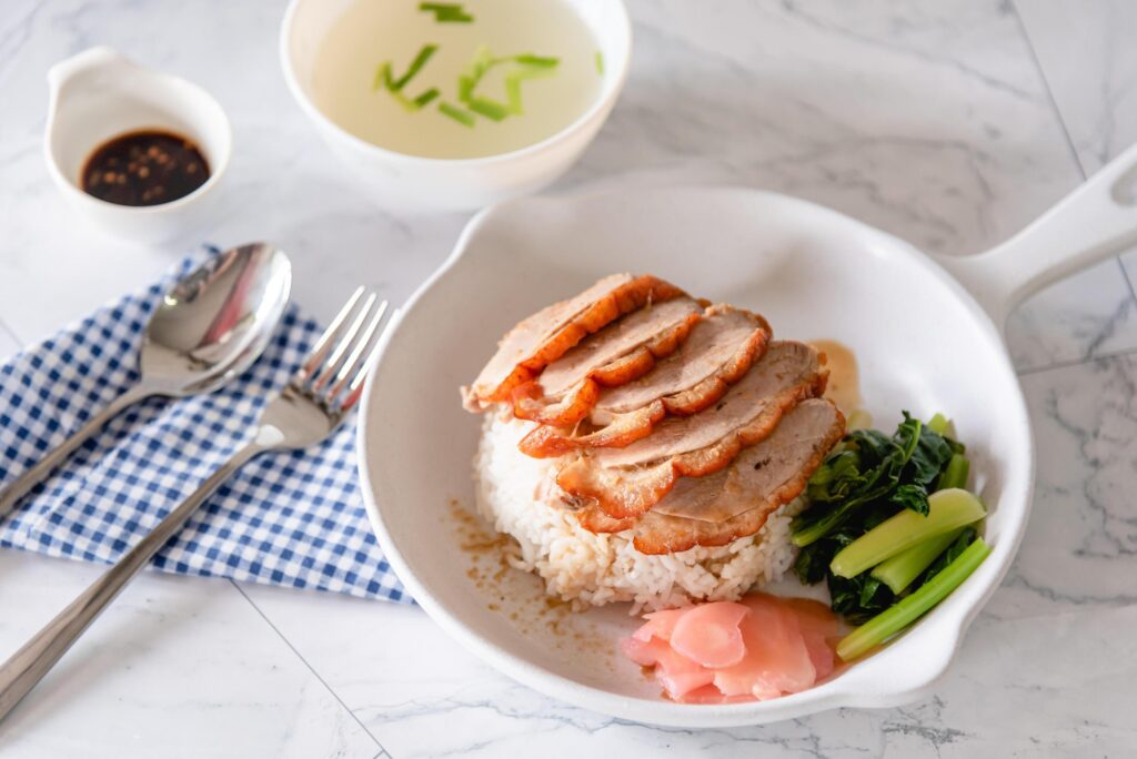 Roasted duck with steam rice, vegetable and pickled ginger on white background as traditional Chinese food Stock Free