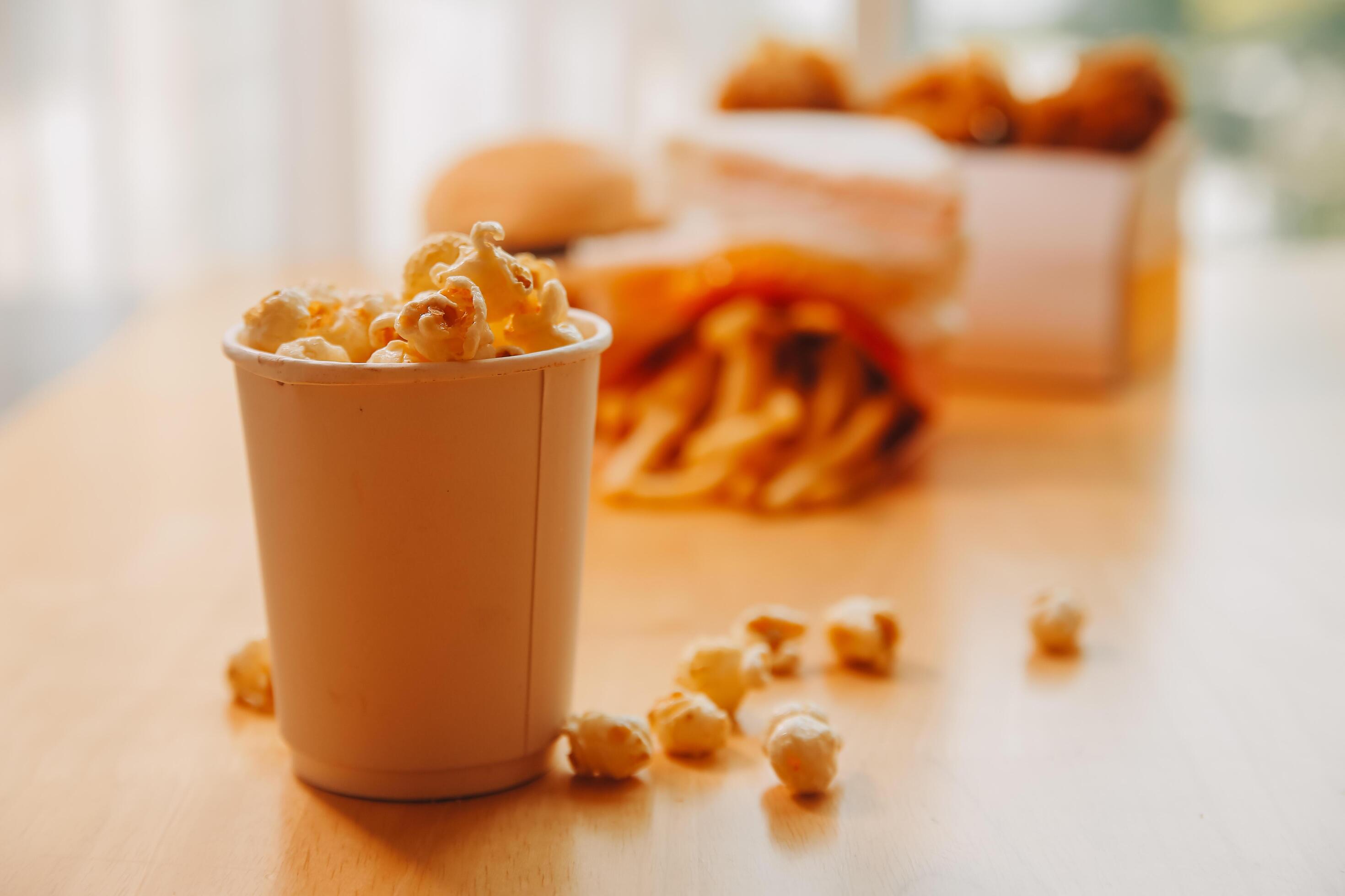 A bucket of popcorn, top-view, warm colors, light brown wooden background, flat lay, daylight macro close-up Stock Free