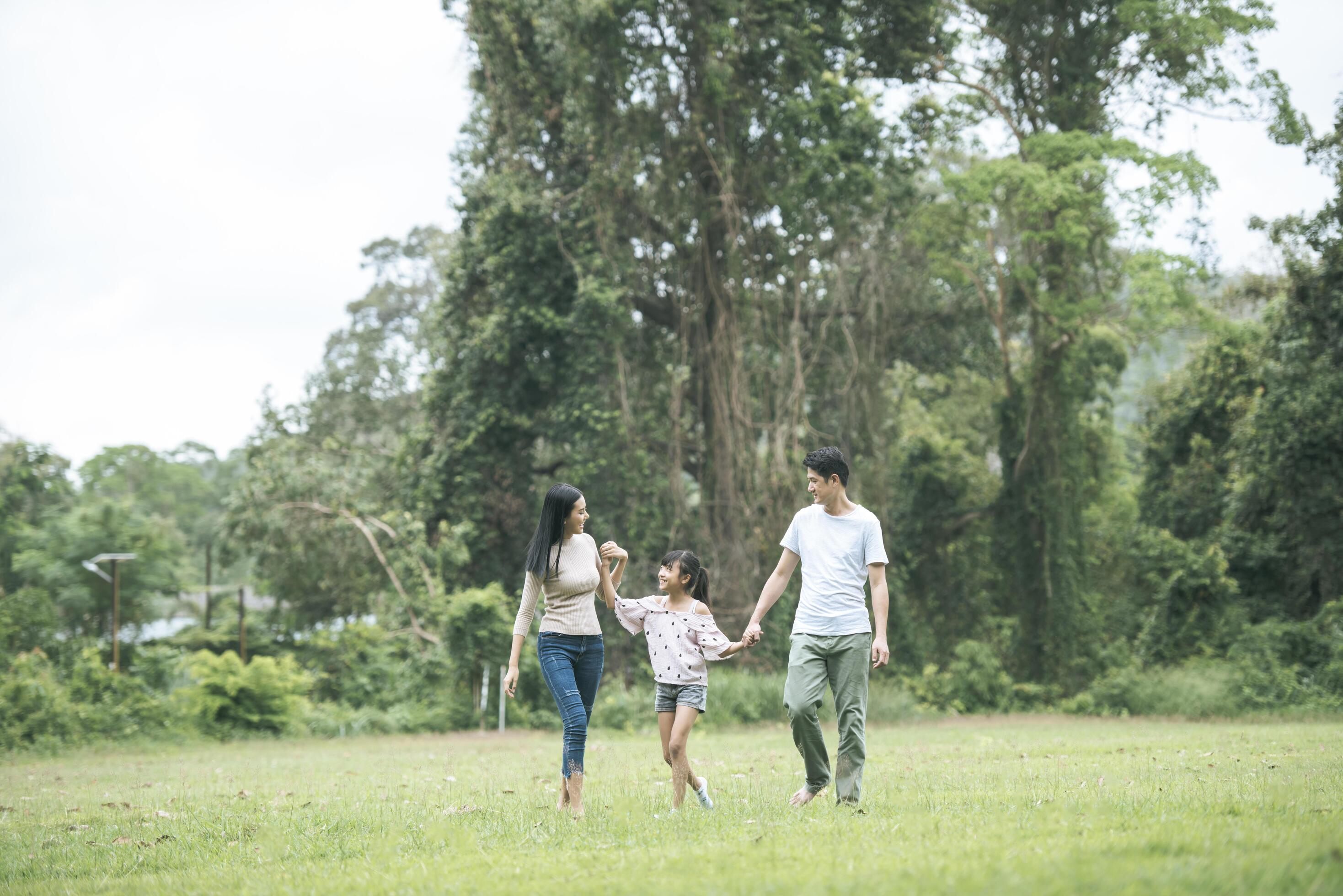 Happy parents and their daughter walking in the park, Happy family concept. Stock Free