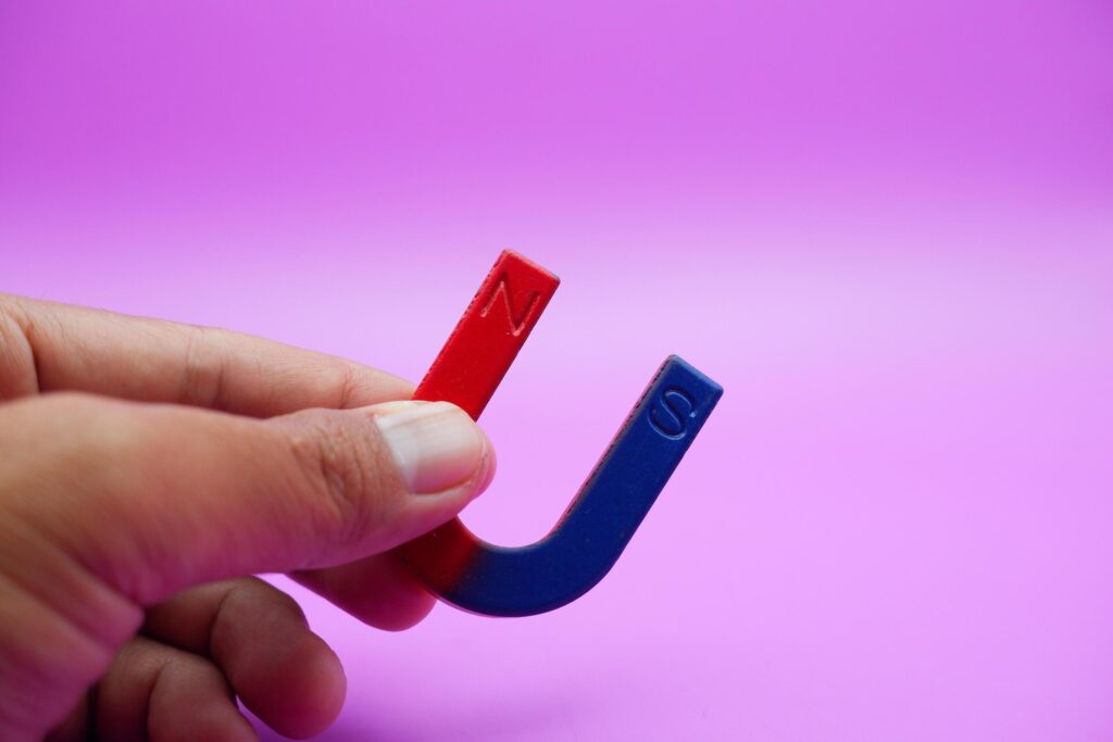 hand holding a horseshoe magnet isolated on a purple background Stock Free