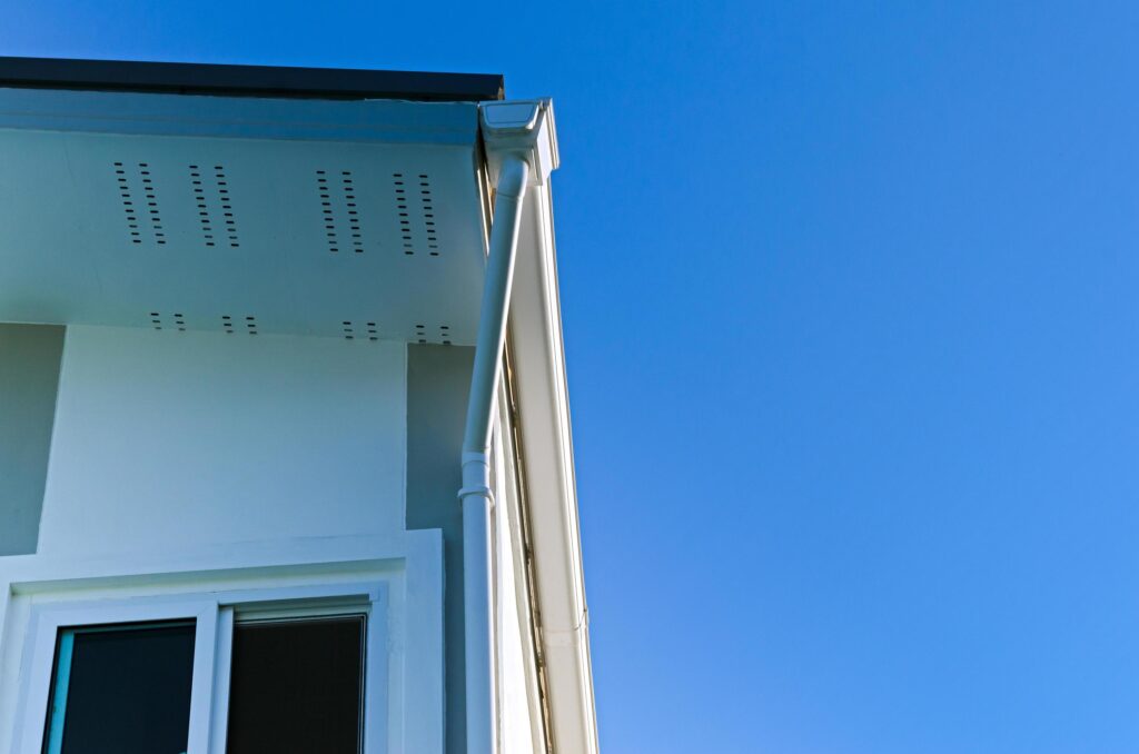 House roof with rain gutter of roof top house and large windows on blue sky background, New modern building Stock Free