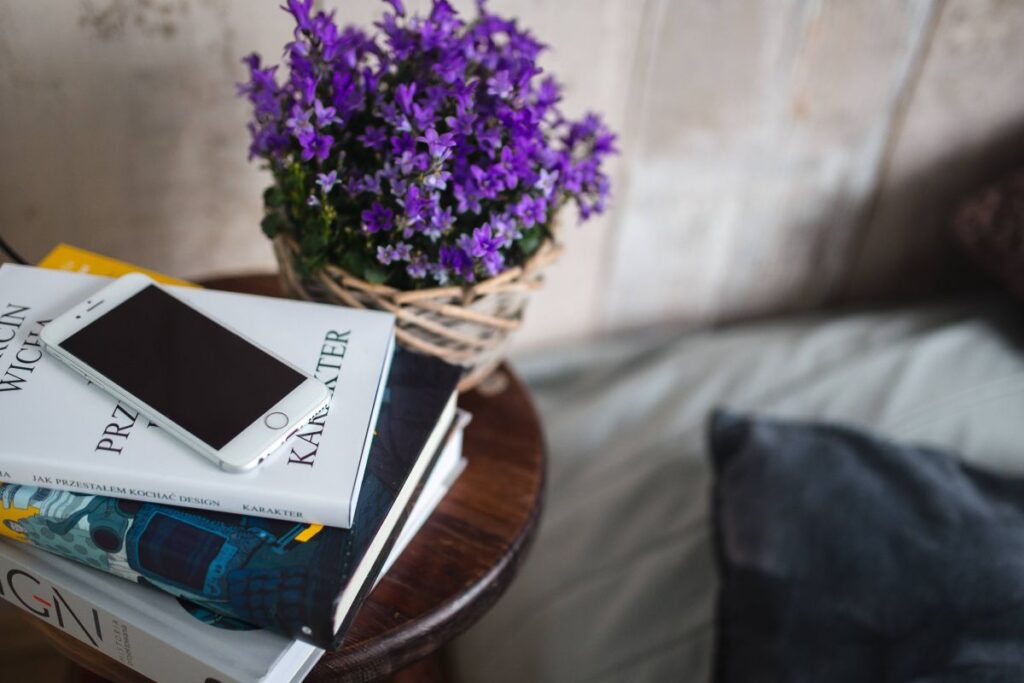 Books and purple flowers on a wooden stool by the bed Stock Free