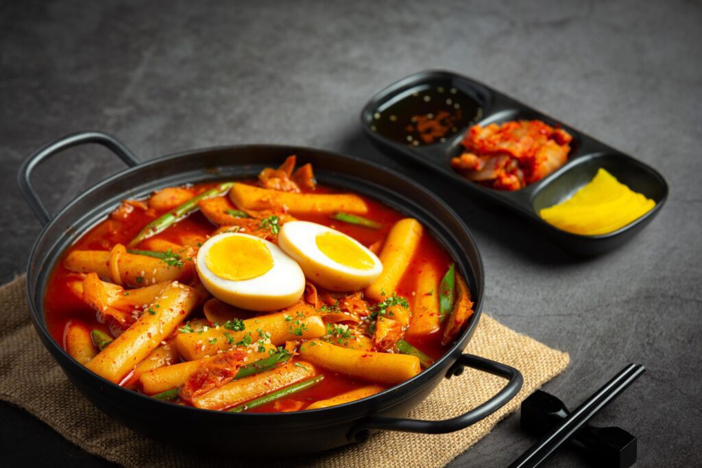 Cheesy Tokbokki korean traditional food on black board background. Lunch dish. Stock Free