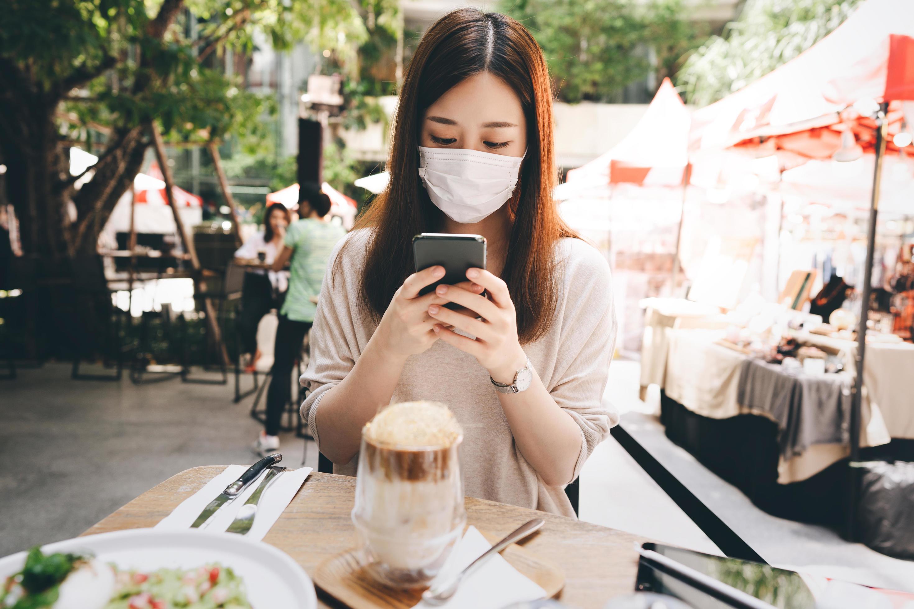 Young adult asian woman wear mask for new normal lifestyle at outdoor restaurant on day Stock Free