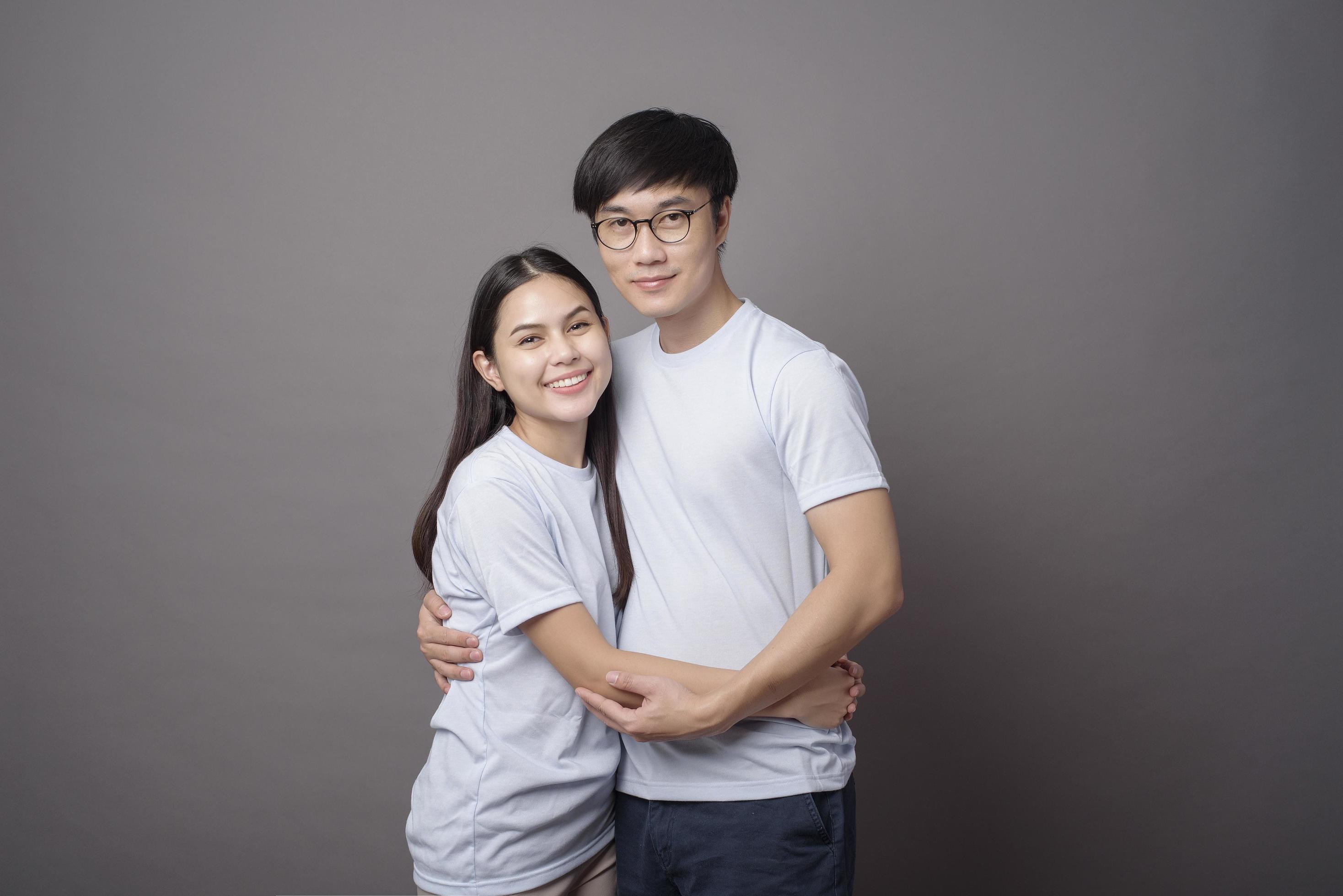 a portriat of a happy couple wearing blue shirt is hugging each other in grey background studio Stock Free