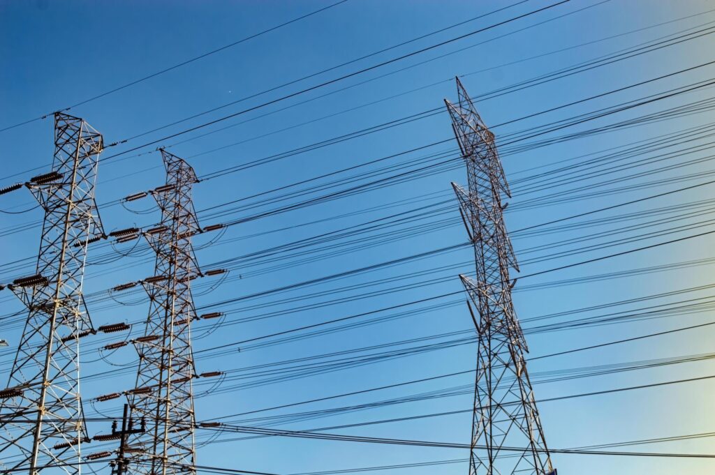 several high voltage power towers against a bright blue sky background Stock Free