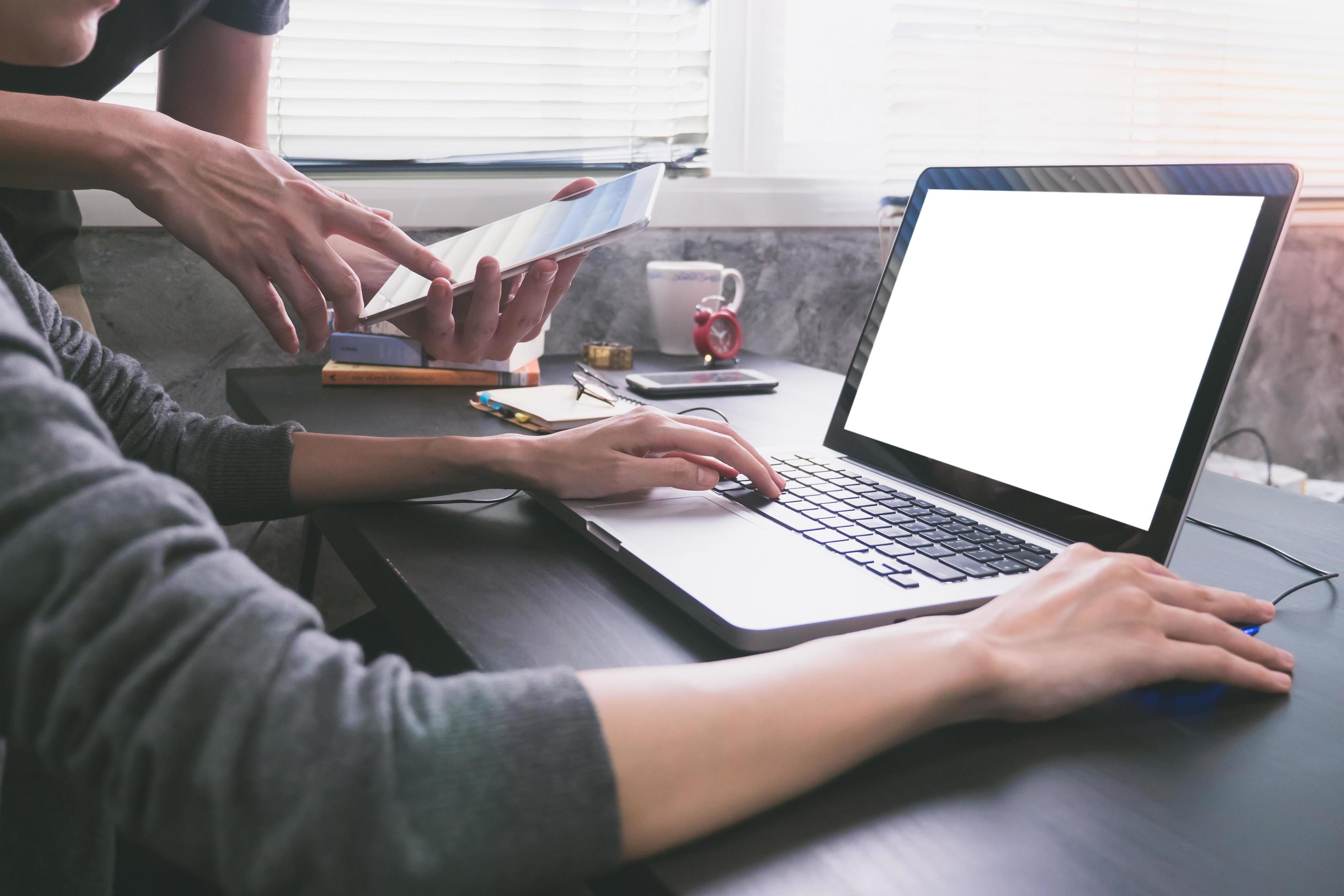 Business partners working together at office desk, they are using a laptop with blank screen and tablet. Stock Free