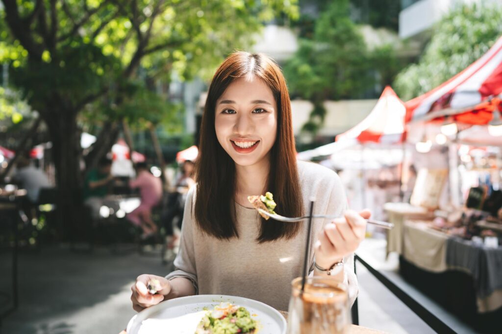 Young adult asian woman eat lunch food at restaurant outdoor on weekend day Stock Free