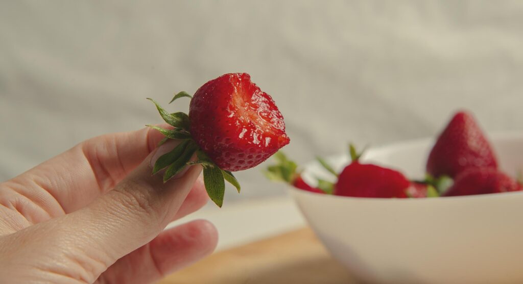 Close-up of strawberries in a woman hands against the background of strawberries in a bowl Stock Free