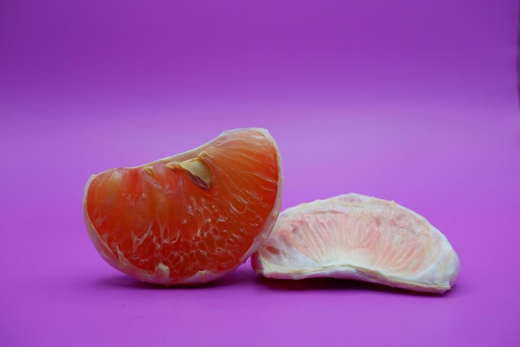 2 grapefruit isolated on purple background. 2 pieces of grapefruit that have been peeled until the grain of the orange is visible Stock Free