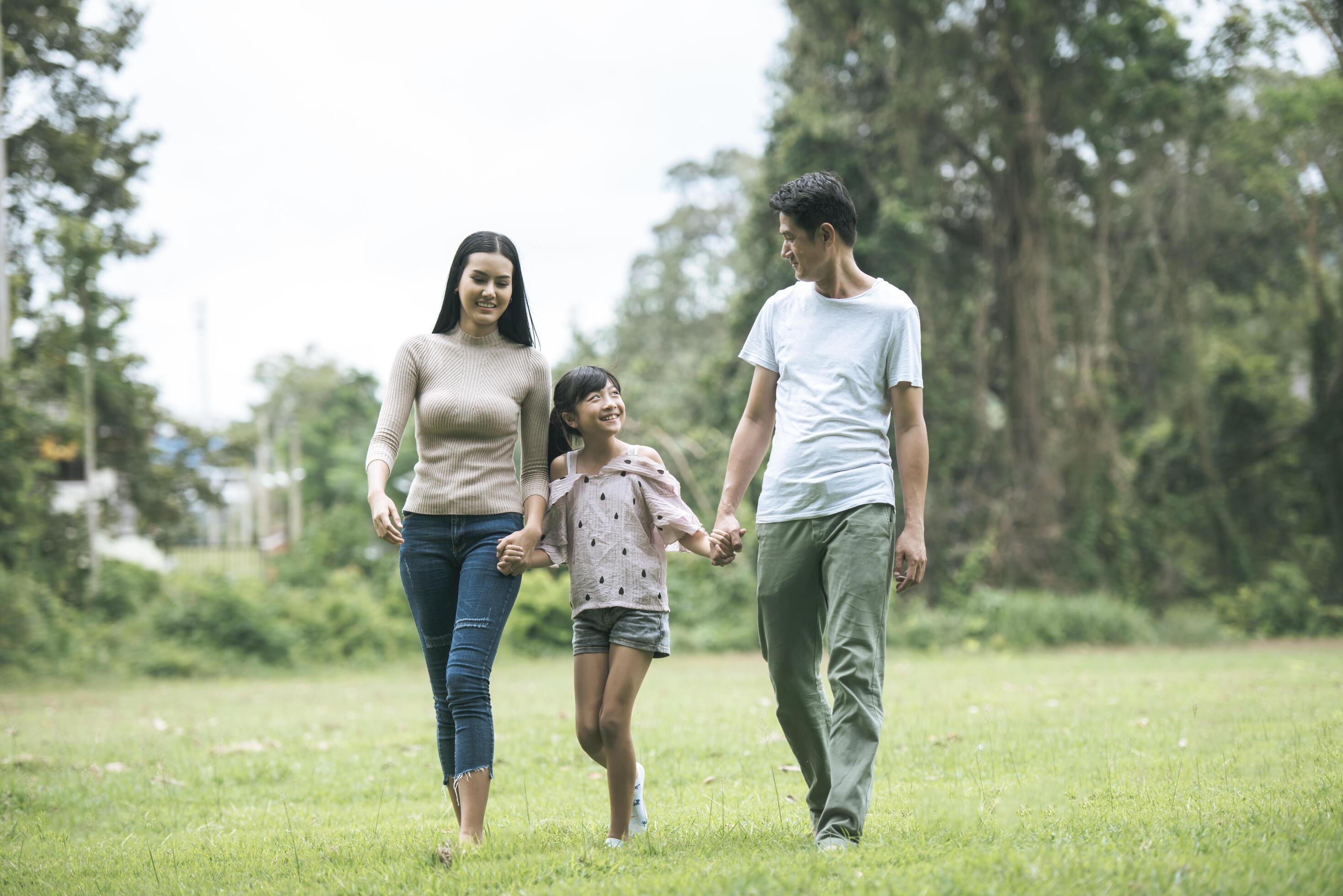 Happy parents and their daughter walking in the park, Happy family concept. Stock Free