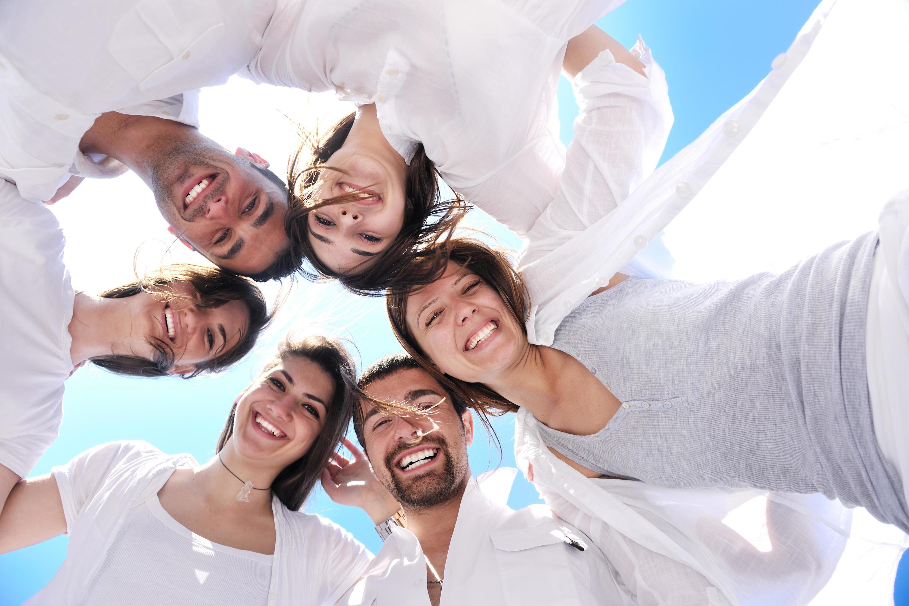 Group of happy young people in circle at beach Stock Free