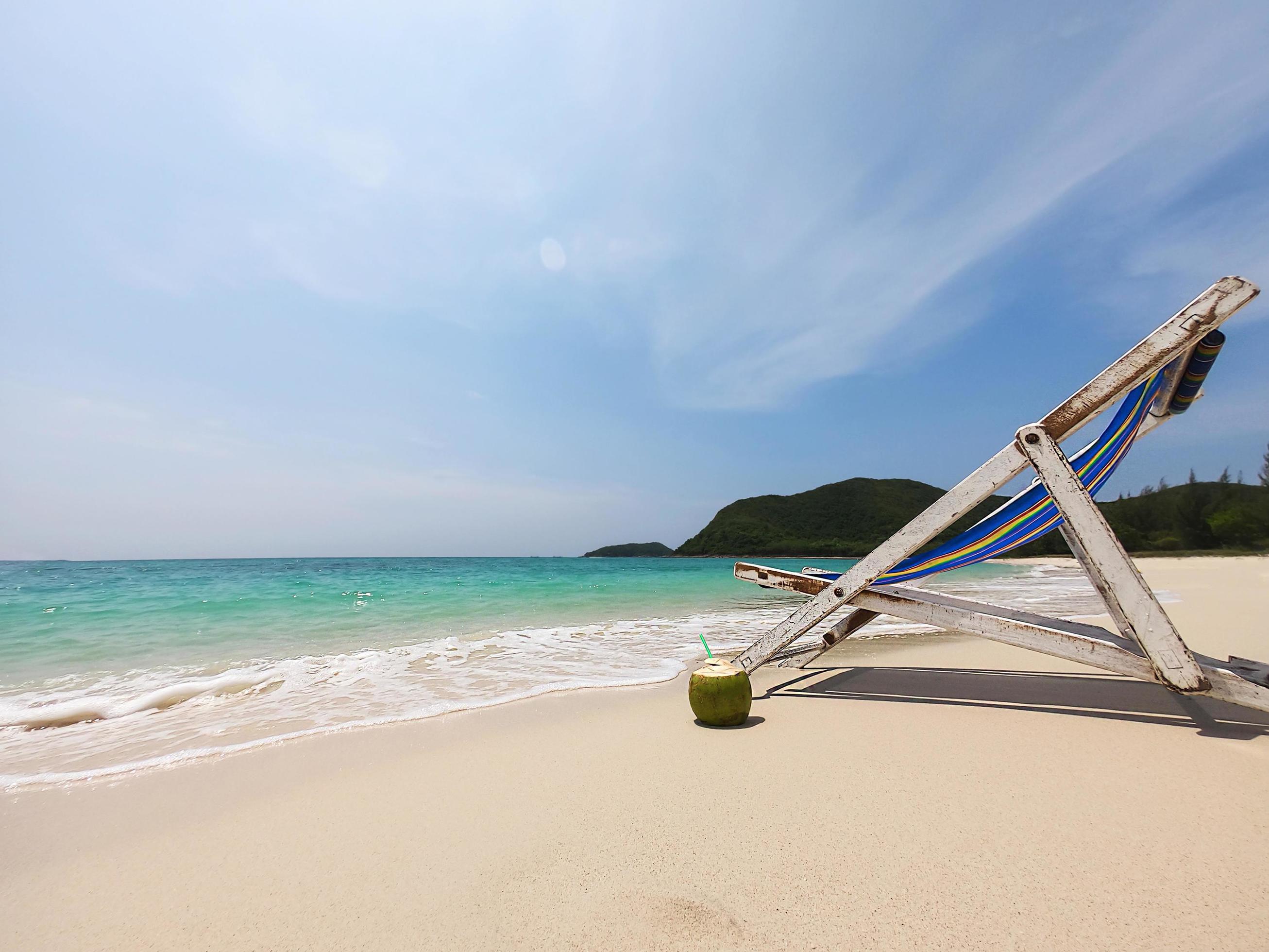 Relax beach chair with fresh coconut on clean sand beach with blue sea and clear sky – sea nature background relax concept Stock Free