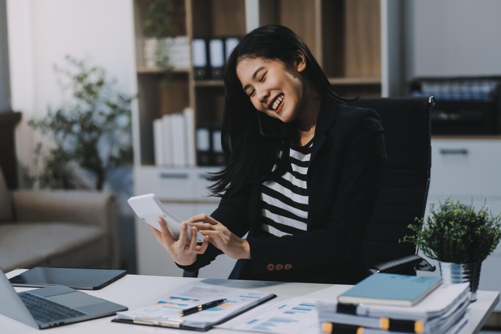 Young Asian businesswoman using a calculator to calculate business principles. Accounting statistics concept at the office. Stock Free