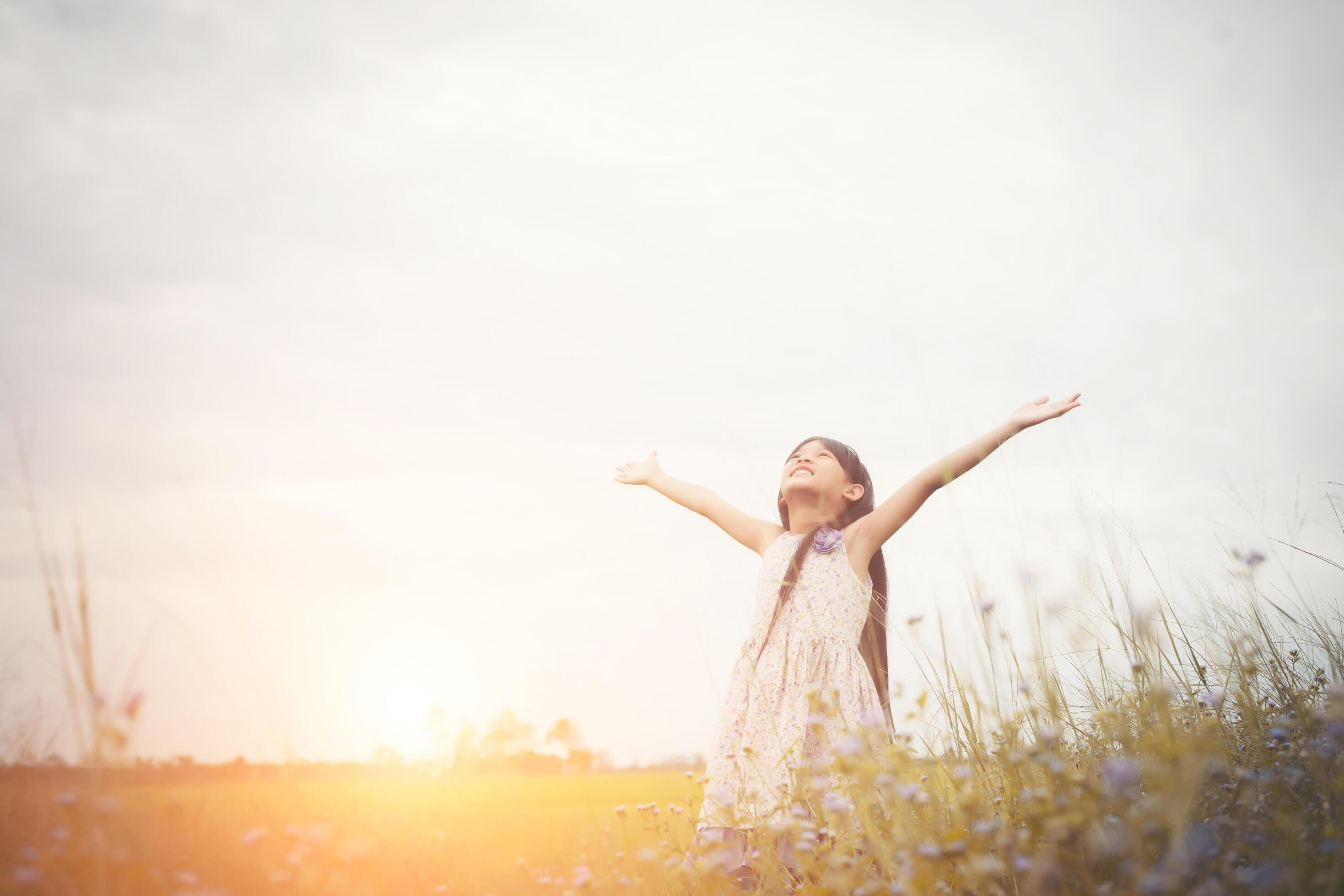 Little cute asian girl standing among the purple flower field sunshine day. Freedom enjoying with nature. Stock Free