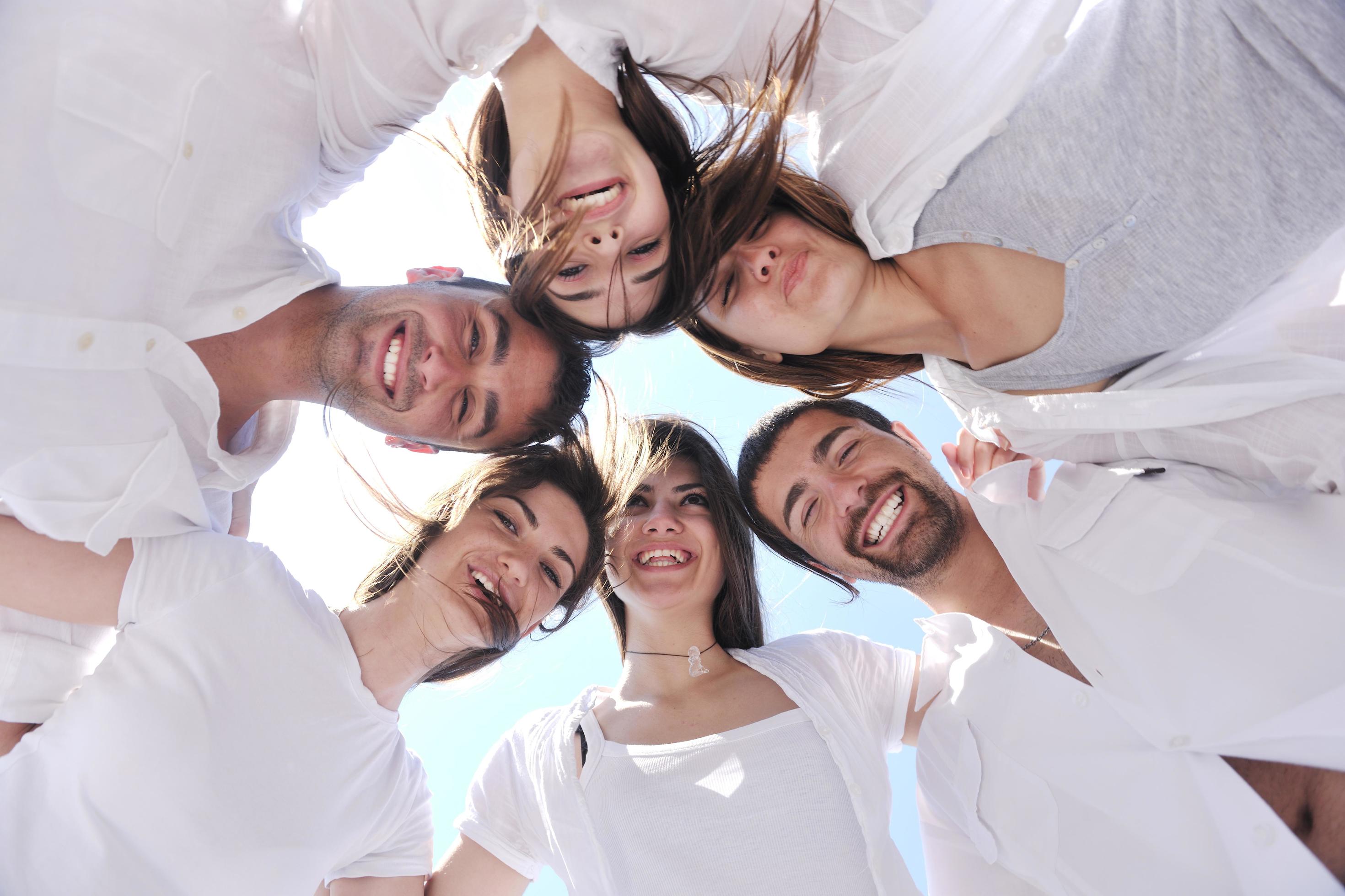 Group of happy young people in circle at beach Stock Free