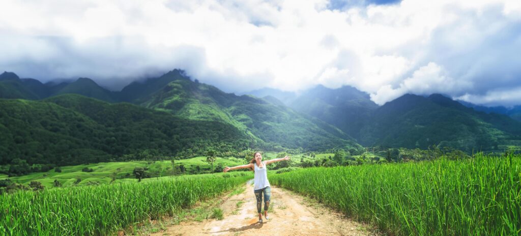 Asian women travel relax in the holiday. Running jumping on the middle of the meadow road Stock Free