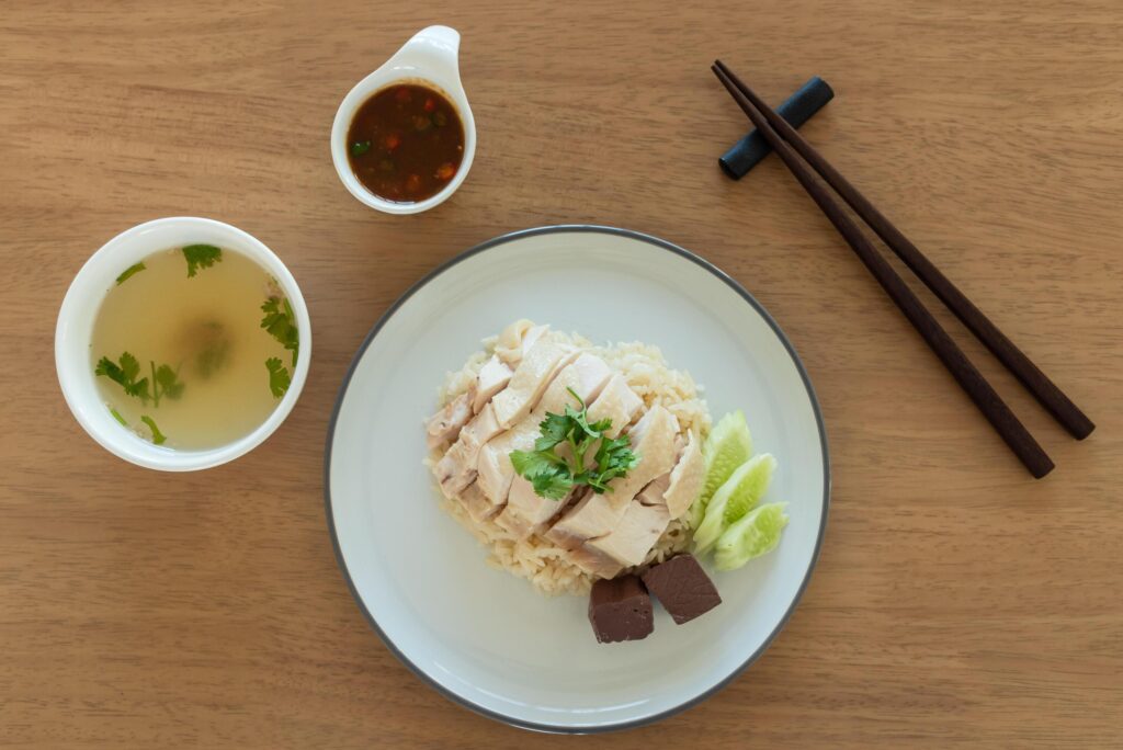 Top view Singapore chicken rice with salted soya beans sauce and soup on wooden background Stock Free