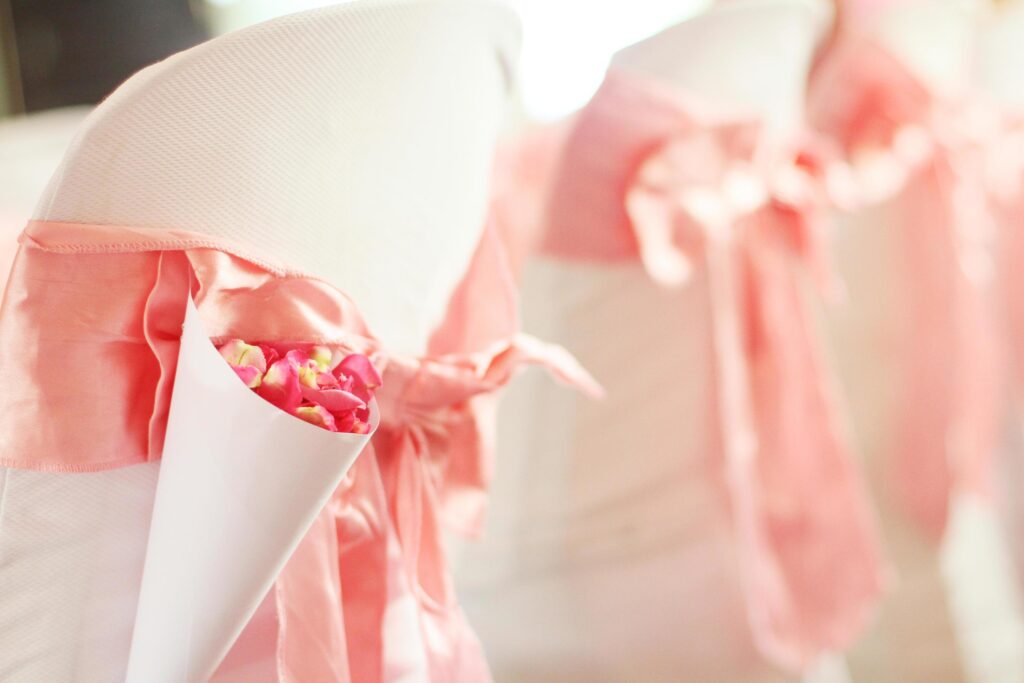 Beautiful Pink Rose petals Flowers with pink ribbon decoration on chairs in wedding event hall. Stock Free