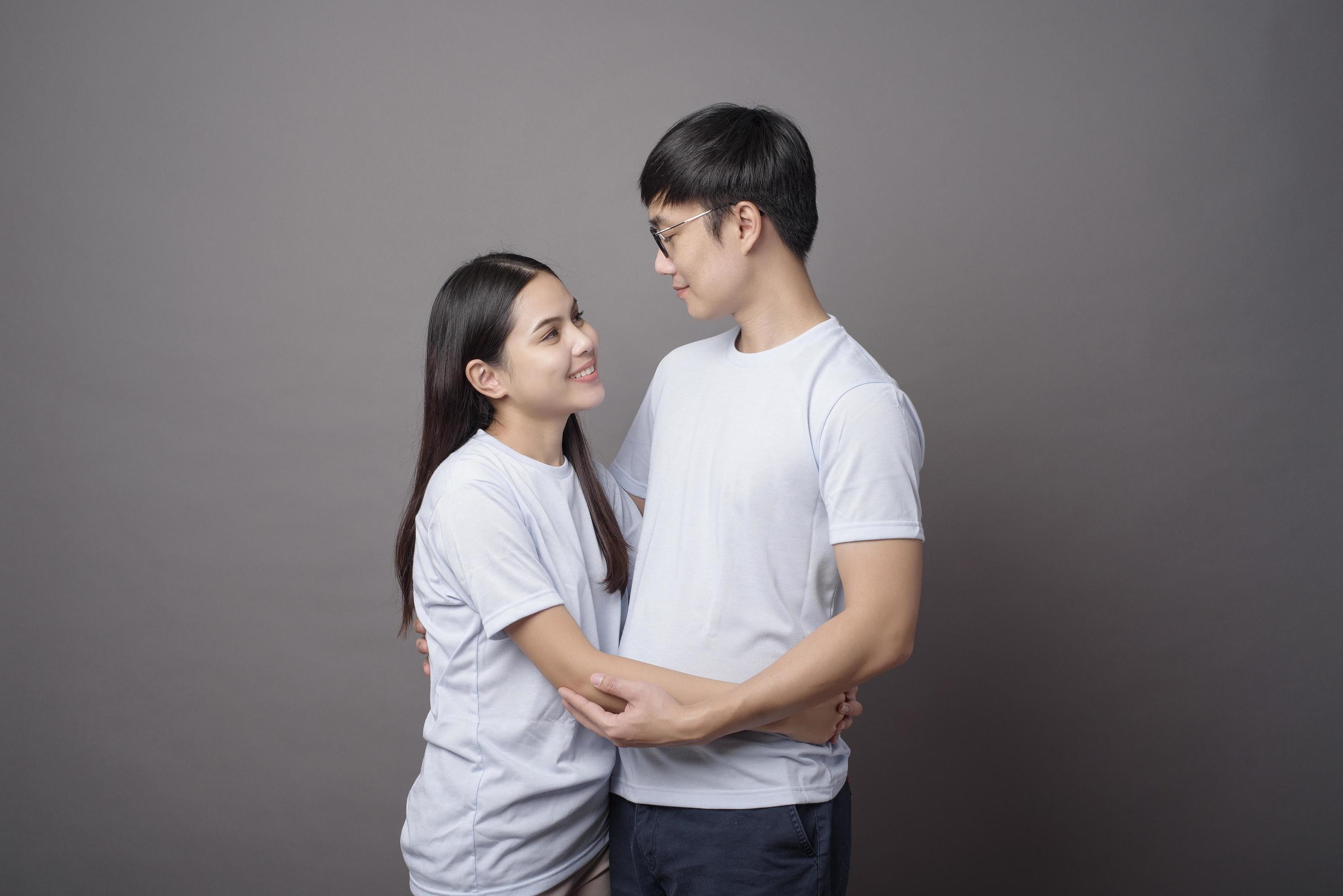 a portriat of a happy couple wearing blue shirt is hugging each other in grey background studio Stock Free