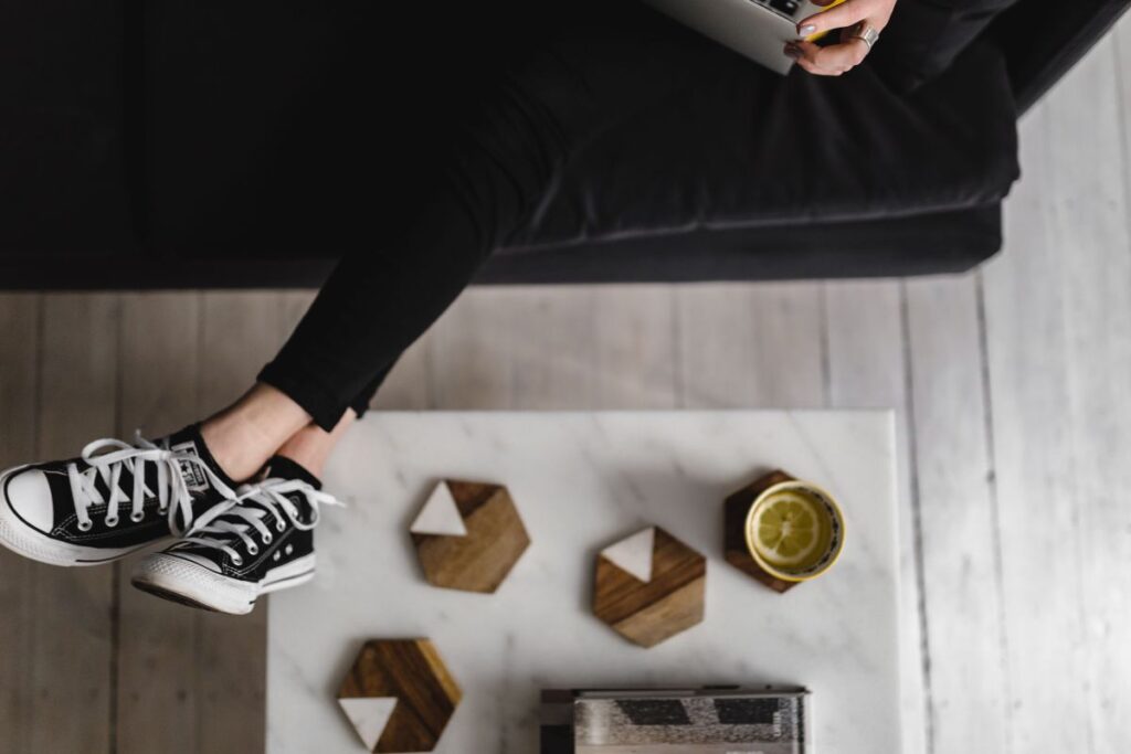 Young woman sitting on the sofa and working on her laptop Stock Free