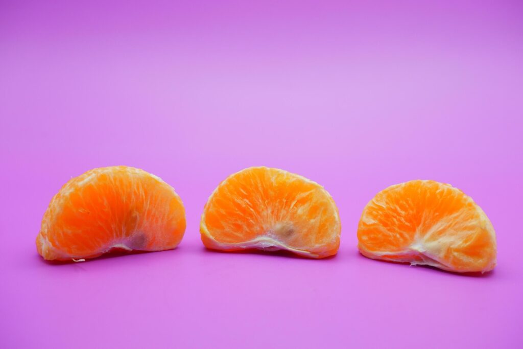 oranges that have been peeled and divided into several parts. orange isolated on purple background Stock Free