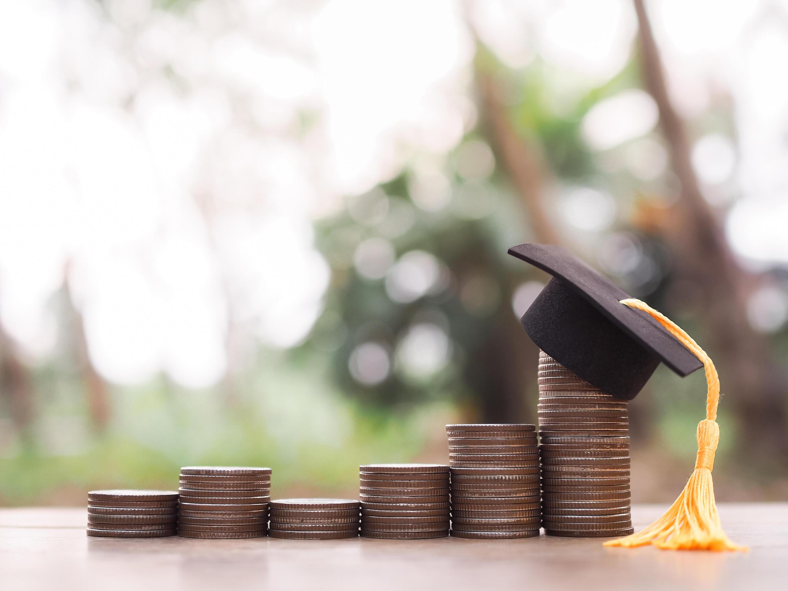 Graduation hat on stack of coins. The concept of saving money for education, student loan, scholarship, tuition fees in future Stock Free