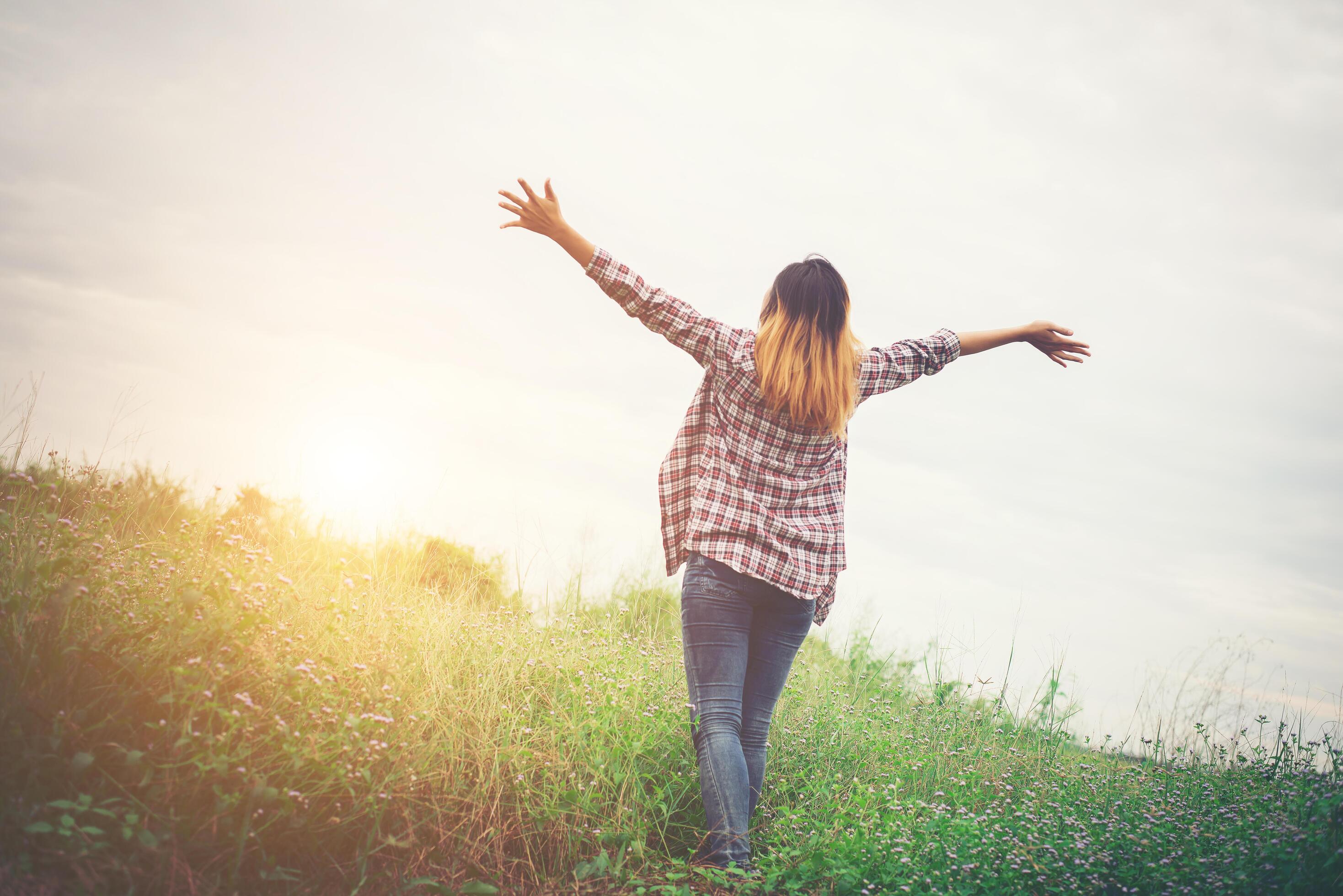 Young beautiful hipster woman in a flower field at sunset. Freedom enjoying with nature. Stock Free