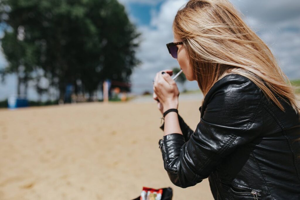 Young woman wearing a leather jacket and sunglasses on the beach Stock Free